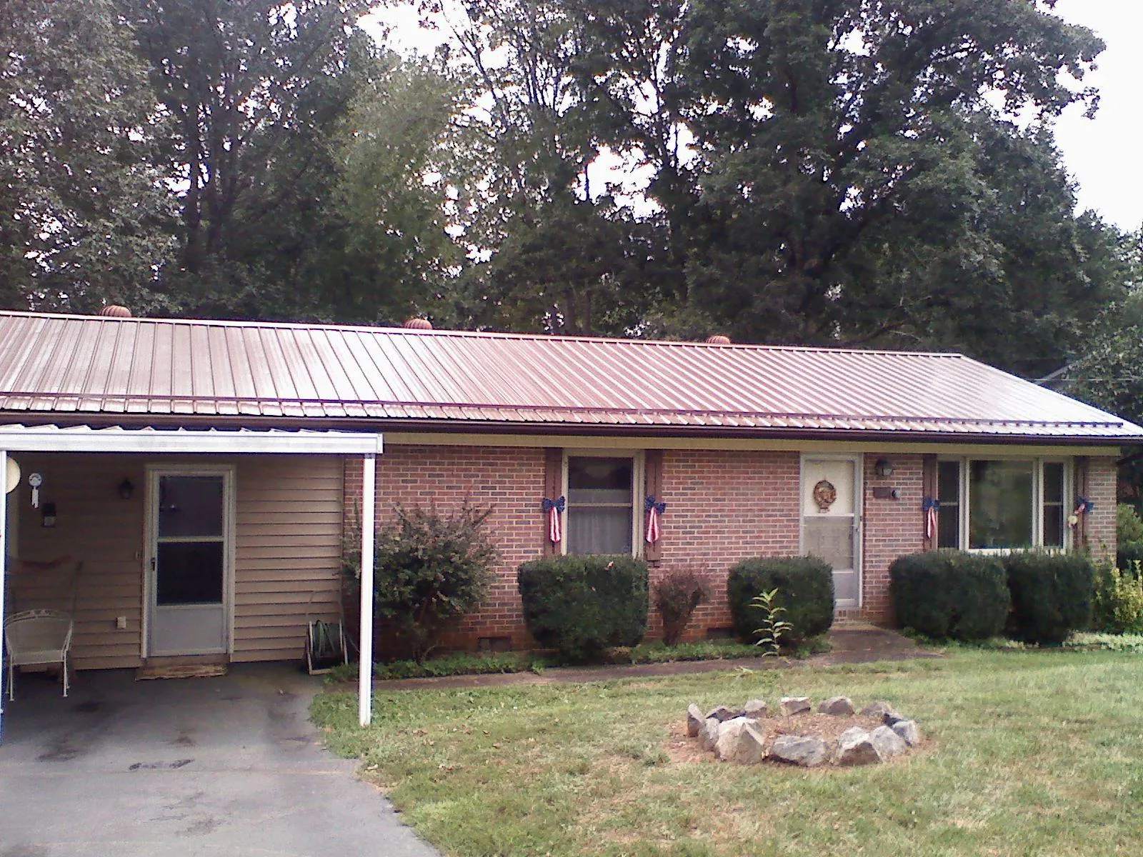 Bronze metal roof and carport on a brick ranch home — Roof Repair work by our crew in Clyde